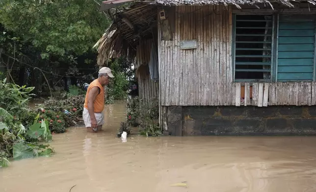 A man wades in floods outside his house caused by Tropical Trami, locally named Kristine, in Polangui, Albay province, Philippines on Oct. 23, 2024. (AP Photo/John Michael Magdasoc)