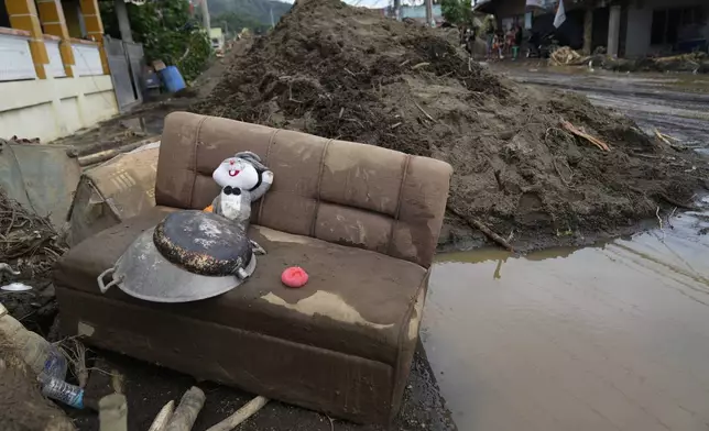 A rabbit doll sits on a mud-covered sofa after a landslide triggered by Tropical Storm Trami struck homes in Talisay, Batangas province, Philippines on Saturday, Oct. 26, 2024. (AP Photo/Aaron Favila)