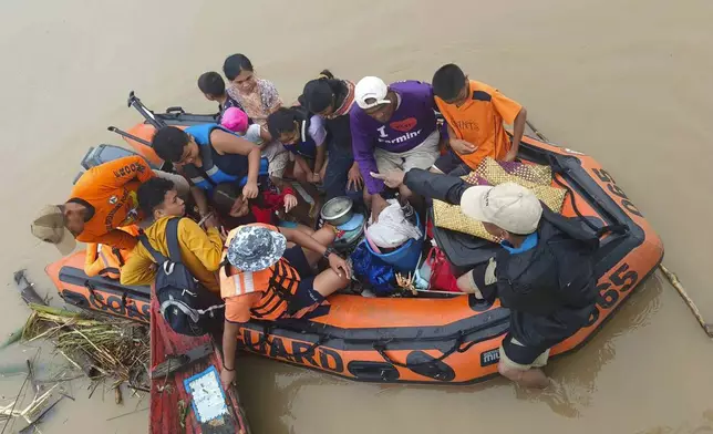 Residents are ferried on a rubber boat after being rescued from their roofs where they stayed to avoid high floods caused by Tropical Storm Trami hit Libon town, Albay province, Philippines on Wednesday Oct. 23, 2024. (Michelle Ricasio via AP)