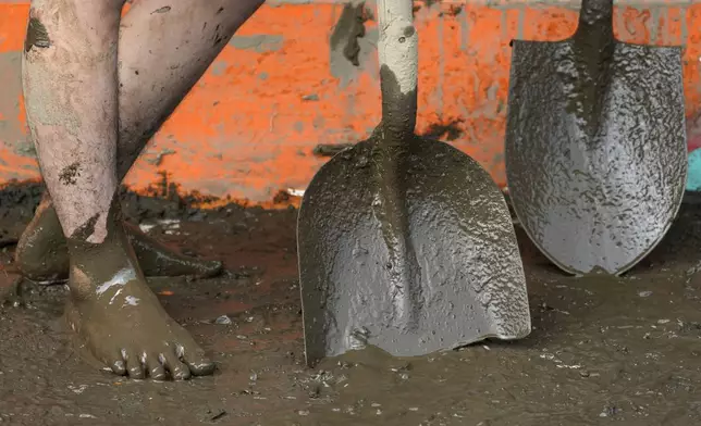 A resident uses shovels as they clean out mud from their house after a landslide triggered by Tropical Storm Trami struck homes in Talisay, Batangas province, Philippines on Saturday, Oct. 26, 2024. (AP Photo/Aaron Favila)