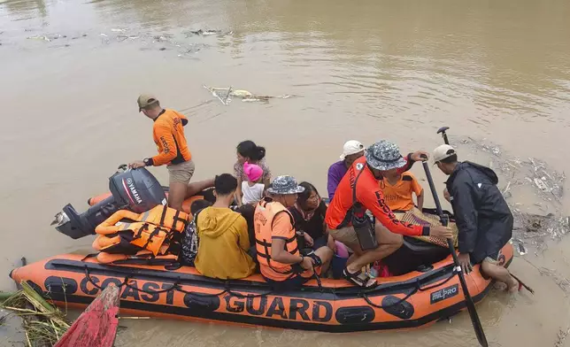 Residents are ferried on a rubber boat after being rescued from their roofs where they stayed to avoid high floods caused by Tropical Storm Trami hit Libon town, Albay province, Philippines on Wednesday Oct. 23, 2024. (Michelle Ricasio via AP)