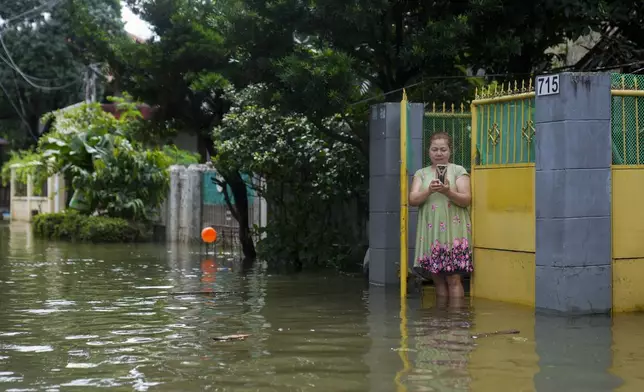 A resident takes pictures of floods caused by Tropical Storm Trami from her home on Friday, Oct. 25, 2024, in Cainta, Rizal province, Philippines. (AP Photo/Aaron Favila)