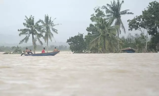 Residents ride a boat as they pass by a house submerged in floodwaters caused by Tropical Storm Trami, locally named Kristine, as it continues to inundate Libon town, Albay province, Philippines on Thursday Oct. 24, 2024. (AP Photo/John Michael Magdasoc)