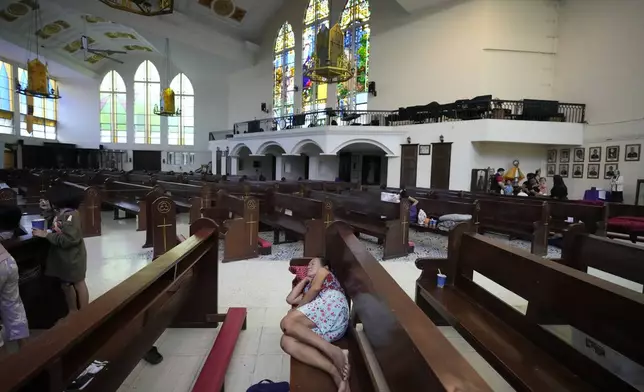 Evacuees rest on pews inside the Holy Family Parish that is used as a temporary evacuation center after floods caused by Tropical Storm Trami, locally named Kristine, inundate their village on Thursday, Oct. 24, 2024, in Quezon city, Philippines. (AP Photo/Aaron Favila)