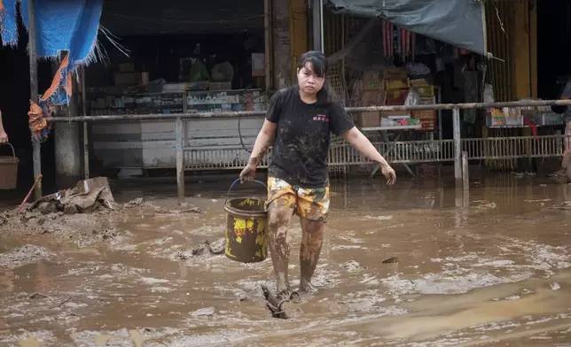 A resident collects mud as they start cleaning their area after floods caused by Tropical Trami, locally named Kristine, in Polangui, Albay province, Philippines on Oct. 23, 2024. (AP Photo/John Michael Magdasoc)