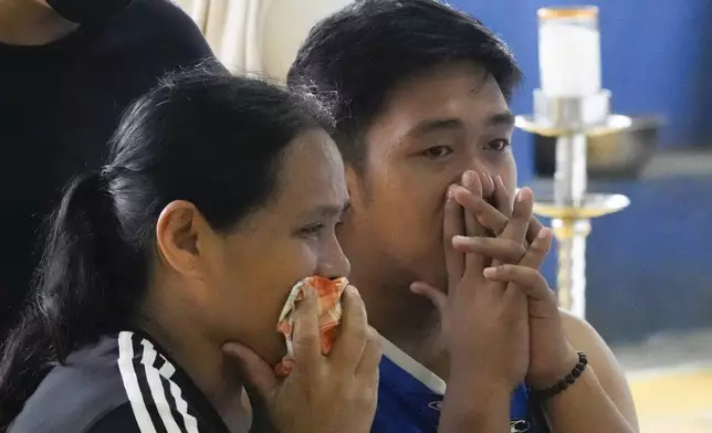 Family and their friend grieve as they watch over their loved ones at a basketball court where the coffins of landslide victims were placed after Tropical Storm Trami recently struck Talisay, Batangas province, Philippines on Saturday, Oct. 26, 2024. (AP Photo/Aaron Favila)