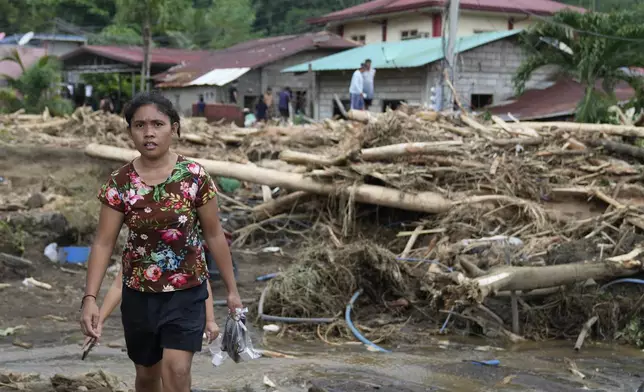 A resident passes by toppled trees after a landslide triggered by Tropical Storm Trami recently struck Talisay, Batangas province, Philippines, Saturday, Oct. 26, 2024. (AP Photo/Aaron Favila)