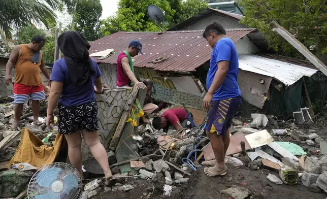 Residents try to recover personal belongings from their damaged home after a landslide triggered by Tropical Storm Trami recently struck Talisay, Batangas province, Philippines, Saturday, Oct. 26, 2024. (AP Photo/Aaron Favila)