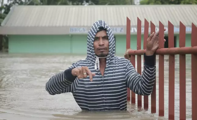 A resident walks along floods caused by Tropical Storm Trami, locally named Kristine, as it continues to inundate Libon town, Albay province, Philippines on Thursday Oct. 24, 2024. (AP Photo/John Michael Magdasoc)