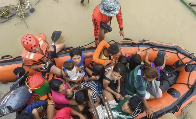 Residents are ferried on a rubber boat after being rescued from their roofs where they stayed to avoid high floods caused by Tropical Storm Trami hit Libon town, Albay province, Philippines on Wednesday Oct. 23, 2024. (Michelle Ricasio via AP)