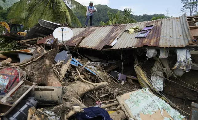 Marcelino Aringo stands on top of a damaged house after a landslide triggered by Tropical Storm Trami recently struck Talisay, Batangas province, Philippines, Saturday, Oct. 26, 2024 . (AP Photo/Aaron Favila)