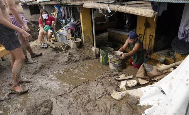 Residents clear out mud from their homes after a landslide triggered by Tropical Storm Trami recently struck Talisay, Batangas province, Philippines, Saturday, Oct. 26, 2024. (AP Photo/Aaron Favila)