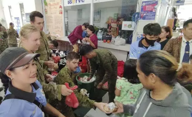 In this handout photo provided by the 9th Infantry Division, Philippine Army, troopers from the 9th Infantry "Spear" Division (9ID) and a contingent from the Australian Army distribute food packs to evacuees affected by Tropical Storm Trami, locally named Kristine, at Naga city, Camarines Sur province, Philippines on Thursday Oct. 24, 2024. (9th Infantry Division, Philippine Army via AP)