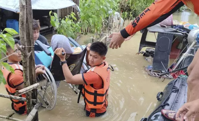 In this handout photo provided by the Philippine Coast Guard, rescuers carry a resident trapped in their homes after floods caused by Tropical Storm Trami, locally named Kristine, hit their village at Libon, Albay province, Philippines on Wednesday Oct. 23, 2024. (Philippine Coast Guard via AP)