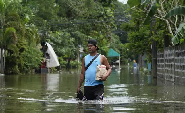 A resident navigates flooded streets caused by Tropical Storm Trami on Friday, Oct. 25, 2024, in Cainta, Rizal province, Philippines. (AP Photo/Aaron Favila)