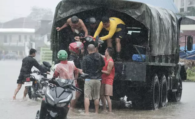 Residents bring down a motorcycle which was recovered at a flooded area on Thursday Oct. 24, 2024 after Tropical Storm Trami, locally named Kristine, dumped heavy rains at Libon town, Albay province, Philippines. (AP Photo/John Michael Magdasoc)