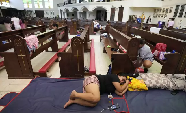 Evacuees rest inside the Holy Family Parish that is used as a temporary evacuation center after floods caused by Tropical Storm Trami, locally named Kristine, inundate their village on Thursday, Oct. 24, 2024, in Quezon city, Philippines. (AP Photo/Aaron Favila)