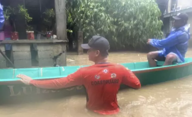 In this photo provided by Philippine Coast Guard, rescuers use a boat to evacuate residents at a flooded village as powerful Typhoon Krathon affects Laoag, Ilocos Norte, northern Philippines Monday, Sept. 30, 2024. (Philippine Coast Guard via AP)