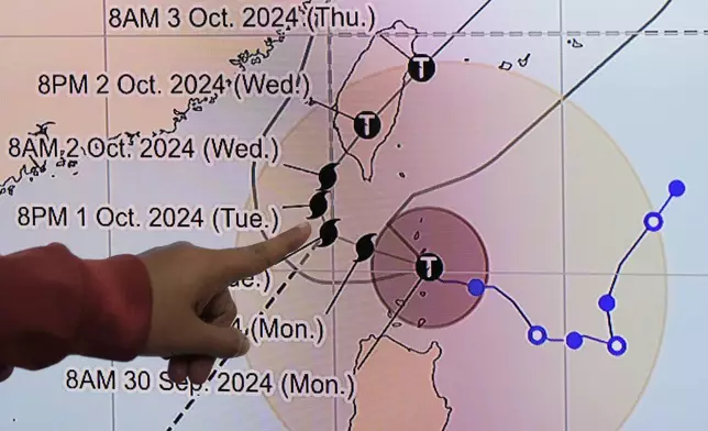 Philippine Atmospheric, Geophysical and Astronomical Services Administration weather specialist Veronica Torres points at the path of powerful Typhoon Krathon on Monday, Sept. 30, 2024, in Quezon city, Philippines as it is projected to go towards Taiwan the next day after hitting northern Philippines. (AP Photo/Aaron Favila)