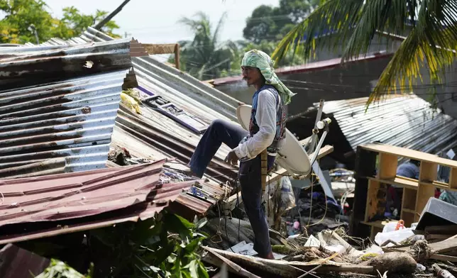 Residents try to recover belongings from their damaged homes after a recent landslide triggered by Tropical Storm Trami struck Talisay, Batangas province, Philippines leaving thousands homeless and several villagers dead on Saturday, Oct. 26, 2024. (AP Photo/Aaron Favila)