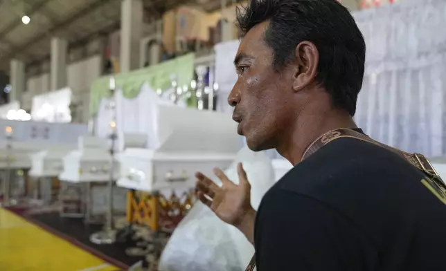 Raynaldo Dejucos speaks beside coffins of the family he lost in a landslide triggered by Tropical Storm Trami during their wake at a basketball court on Saturday, Oct. 26, 2024, in Talisay, Batangas province, Philippines. (AP Photo/Aaron Favila)