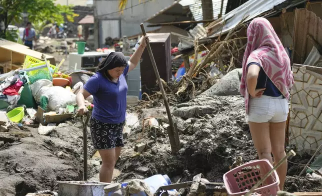 Residents try to recover belongings from their damaged homes after a recent landslide triggered by Tropical Storm Trami struck Talisay, Batangas province, Philippines leaving thousands homeless and several villagers dead on Saturday, Oct. 26, 2024. (AP Photo/Aaron Favila)