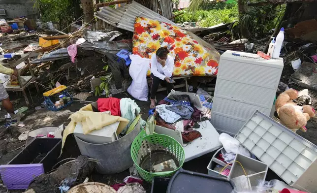 A resident sits beside belongings from their damaged home after a recent landslide triggered by Tropical Storm Trami struck Talisay, Batangas province, Philippines leaving thousands homeless and several villagers dead on Saturday, Oct. 26, 2024. (AP Photo/Aaron Favila)