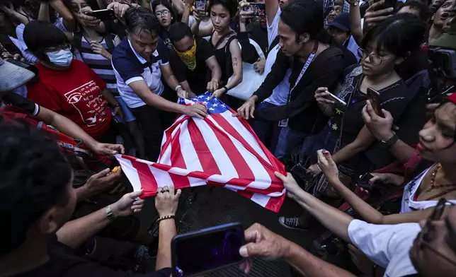 Activists tear a U.S. flag during a rally near the U.S. Embassy in Manila Saturday, Oct. 5, 2024, as they hold a protest to observe the first-year anniversary of the war in Gaza.(AP Photo/Gerard V. Carreon)