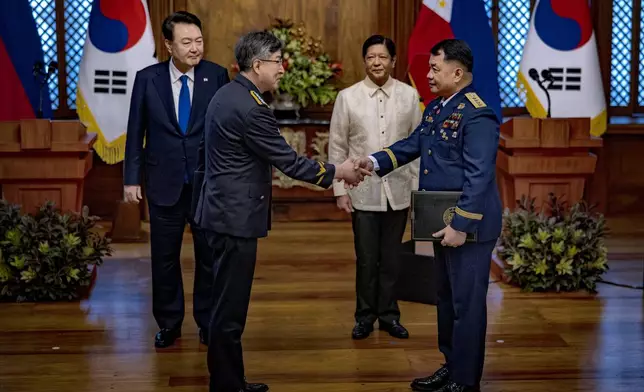 Philippine President Ferdinand Marcos Jr., second right, and South Korean President Yoon Suk Yeol, left, look on as Kim Jong-Uk, second left, Commissioner General of the Korea Coast Guard, and Ronnie Gil Gavan, Commandant of the Philippine Coast Guard, shake hands during a meeting during a meeting at the Malacanang Palace Monday, Oct. 7, 2024 in Manila, Philippines. (Ezra Acayan/Pool Photo via AP)