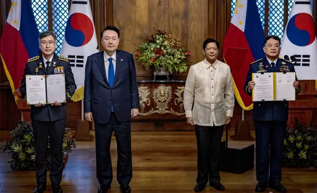 Philippine President Ferdinand Marcos Jr., second right, and South Korean President Yoon Suk Yeol, second left, pose for pictures as Kim Jong-Uk, left, Commissioner General of the Korea Coast Guard, and Ronnie Gil Gavan, Commandant of the Philippine Coast Guard, hold up signed agreement during a meeting at the Malacanang Palace Monday, Oct. 7, 2024 in Manila, Philippines. (Ezra Acayan/Pool Photo via AP)