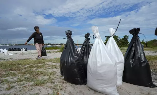 Susana Ortiz fills out sand bags on the beach at the Davis Islands Yacht Basin as she prepares for the arrival of Hurricane Milton, Tuesday, Oct. 8, 2024, in Tampa, Fla. (AP Photo/Julio Cortez)