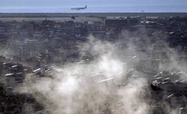 A Middle East Airlines airplane comes in for a landing at Beirut International Airport as smoke rises from Israeli airstrikes in Dahiyeh, in the southern suburb of Beirut, Lebanon, Thursday, Oct. 24, 2024. (AP Photo/Bilal Hussein)