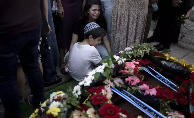 Relatives pause at the grave of Israel Defense Forces Captain Elad Siman Tov, who was killed in action in Lebanon, during his funeral in Petah Tikva, Israel, Friday, Oct. 18, 2024. (AP Photo/Maya Alleruzzo)