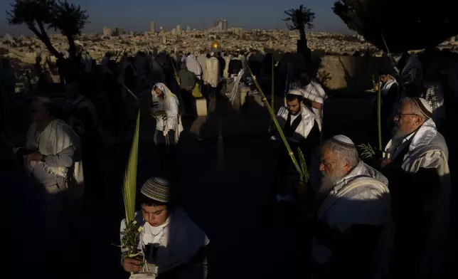 Ultra-Orthodox Jews wearing prayer shawls perform the Hoshana Rabbah prayer on the seventh day of the weeklong Jewish holiday of Sukkot at Mount of Olives overlooking Jerusalem's Old City with the Dome of the Rock shrine, Wednesday, Oct. 23, 2024. (AP Photo//Oded Balilty)