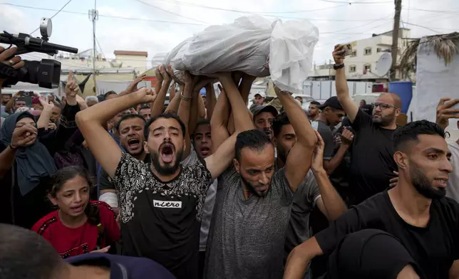 Palestinians mourn as they carry the body of a relative killed in the Israeli bombardment of the Gaza Strip at a hospital in Deir al-Balah, Tuesday, Oct. 8, 2024. (AP Photo/Abdel Kareem Hana)