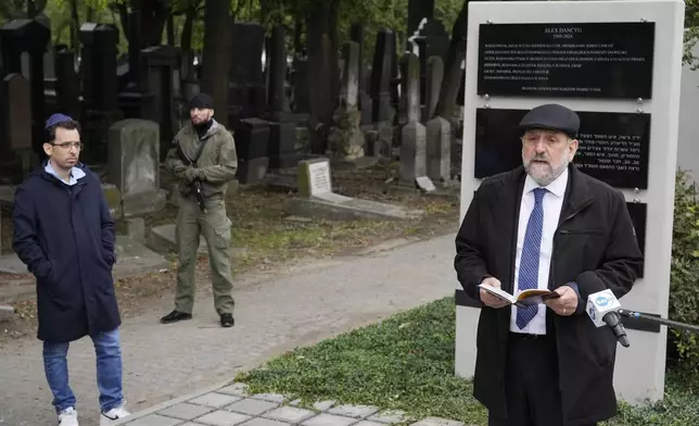 Yuval Danzig, left, the son of a Polish-Israeli man kidnapped and killed by Hamas, and Poland's chief rabbi Michael Schudrich unveil a plaque honoring his father, Alex Dancyg, in the Jewish cemetery in Warsaw, Poland, on Monday, Oct. 7, 2024. (AP Photo/Czarek Sokolowski)