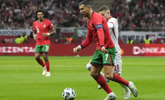 Portugal's Cristiano Ronaldo, front, and Poland's Sebastian Szymanski compete for the ball during the UEFA Nations League soccer match between Poland and Portugal at Narodowy stadium in Warsaw, Poland, Saturday, Oct. 12, 2024. (AP Photo/Czarek Sokolowski)