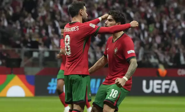 Portugal's Bruno Fernandes, left, is congratulated after assisting Bernardo Silva for his side's opening goal during the UEFA Nations League soccer match between Poland and Portugal at Narodowy stadium in Warsaw, Poland, Saturday, Oct. 12, 2024. (AP Photo/Czarek Sokolowski)