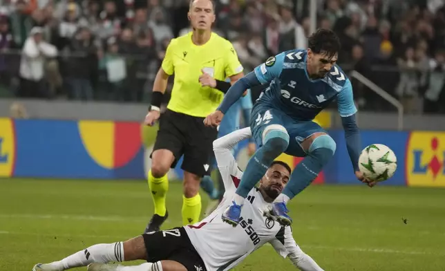 Legia Warsaw's Luquinhas fights for the ball with Real's Johnny Cardoso, top, during the Europa League soccer match between Legia Warsaw and Betis in Warsaw, Poland, Thursday Oct. 3, 2024. (AP Photo/Czarek Sokolowski)