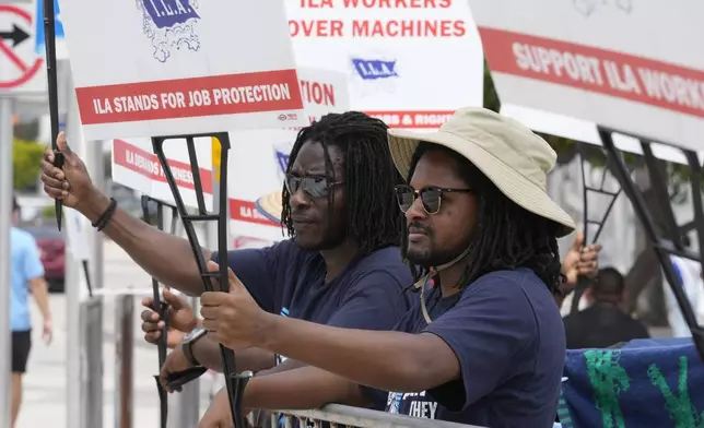 Dockworkers from Port Miami display signs at a picket line, Thursday, Oct. 3, 2024, in Miami. (AP Photo/Marta Lavandier)