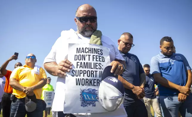 Longshoremen bow for a prayer during a strike at the Bayport Container Terminal on Tuesday, Oct. 1, 2024, in Houston. (AP Photo/Annie Mulligan)