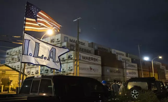 The International Longshoremen’s Association flag and an American flag fly together outside the Packer Avenue Marine Terminal Port as workers prepare to strike as their contract runs out at midnight, Monday, Sept. 30, 2024. (AP Photo/Ryan Collerd)