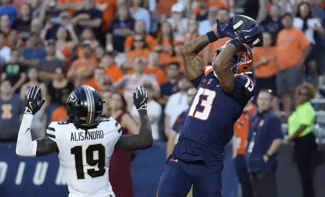 Illinois wide receiver Pat Bryant catches a touchdown pass from quarterback Luke Altmyer as Purdue defensive back Botros Alisandro defends during the overtime period of an NCAA college football game Saturday, Oct. 12, 2024, in Champaign, Ill. Illinois won 50-49. (AP Photo/Charles Rex Arbogast)