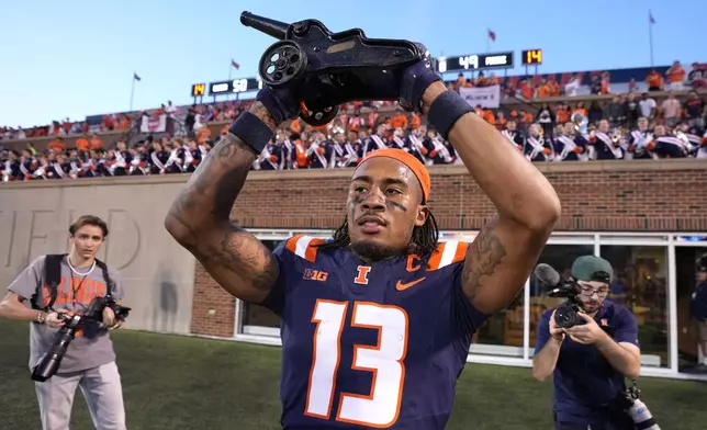 Illinois wide receiver Pat Bryant celebrates with the Purdue cannon after the team's 50-49 overtime win over Purdue in an NCAA college football game Saturday, Oct. 12, 2024, in Champaign, Ill. (AP Photo/Charles Rex Arbogast)