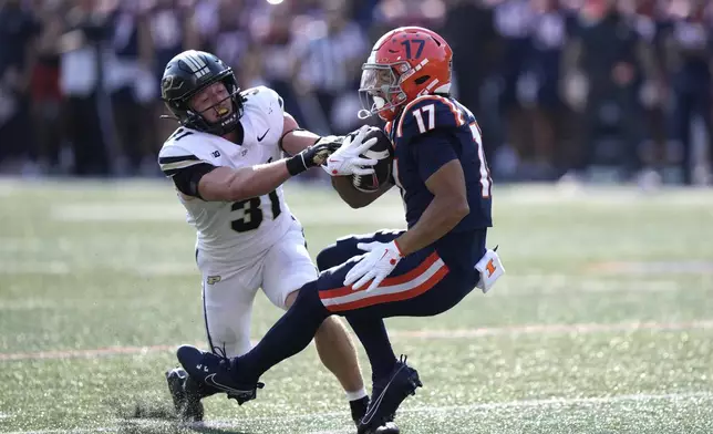 Illinois wide receiver Collin Dixon catches a pass from quarterback Luke Altmyer as Purdue defensive back Dillon Thieneman defends during the first half of an NCAA college football game Saturday, Oct. 12, 2024, in Champaign, Ill. (AP Photo/Charles Rex Arbogast)