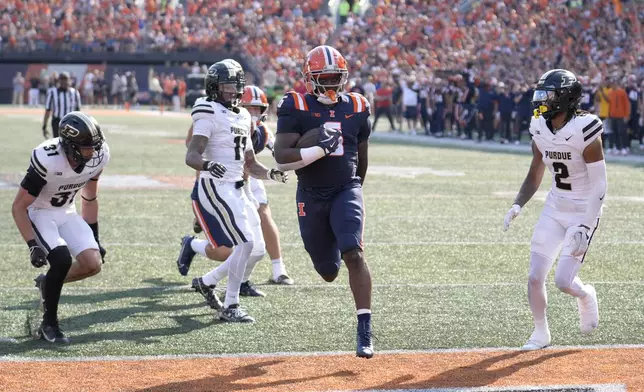 Illinois running back Josh McCray scores between Purdue defensive back Dillon Thieneman, left, and defensive back Nyland Green during the first half of an NCAA college football game Saturday, Oct. 12, 2024, in Champaign, Ill. (AP Photo/Charles Rex Arbogast)