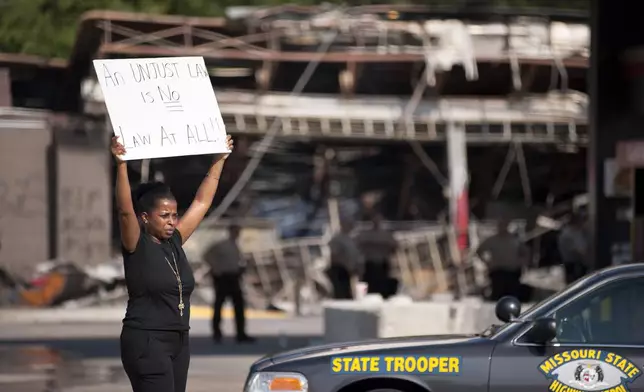 FILE - Protesters appeal to motorists for support while rallying on Aug. 11, 2014 in front of the QT gas station in Ferguson, Mo. that was looted and burned during rioting overnight that followed a candlelight vigil honoring 18-year-old Michael Brown, who was shot on Aug. 9, 2014 by Ferguson police officers. (AP Photo/Sid Hastings)