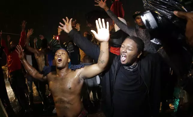 FILE - People defy a curfew on Aug. 17, 2014, before tear gas was fired to disperse a crowd protesting the shooting of teenager Michael Brown in Ferguson, Mo. (AP Photo/Charlie Riedel, File)