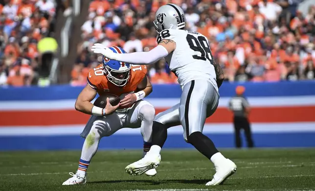 Denver Broncos quarterback Bo Nix (10) is sacked by Las Vegas Raiders defensive end Maxx Crosby (98) during the first half of an NFL football game, Sunday, Oct. 6, 2024, in Denver. (AP Photo/Geneva Heffernan)