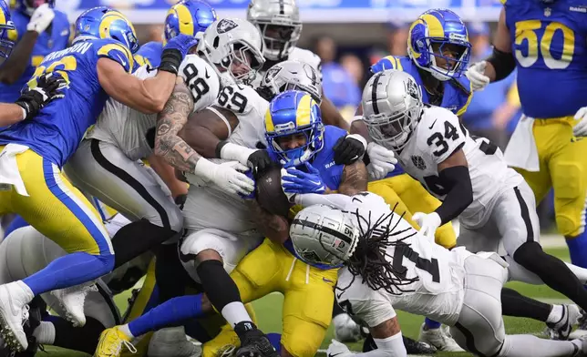 Las Vegas Raiders defensive tackle Adam Butler (69), safeties Thomas Harper (34) and Tre'von Moehrig (7) tackle Los Angeles Rams running back Kyren Williams (23) during the first half of an NFL football game Sunday, Oct. 20, 2024, in Inglewood, Calif. (AP Photo/Marcio Jose Sanchez)